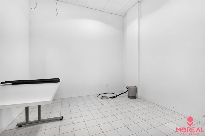 An empty interior with white walls, a table, and white tiles in commercial premises.