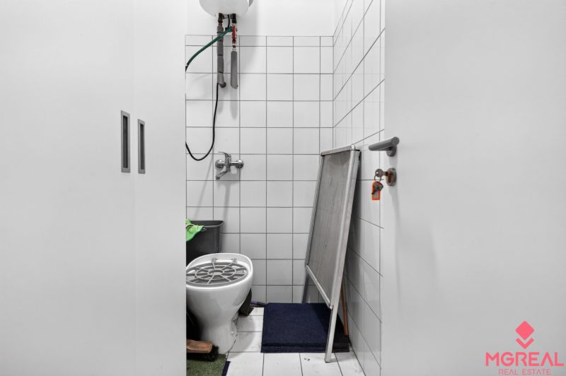 A small room in commercial premises, with a toilet and storage space.