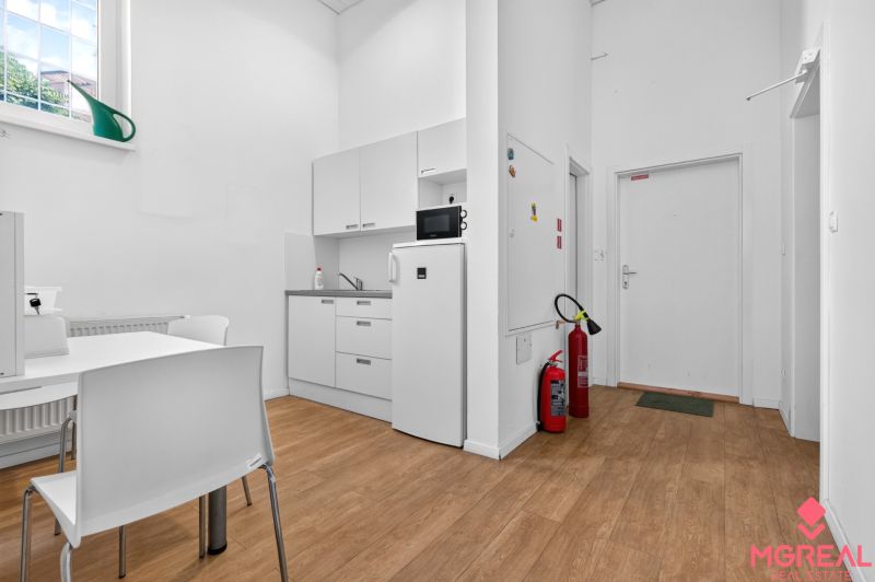 White kitchenette with wood-patterned flooring in commercial premises.