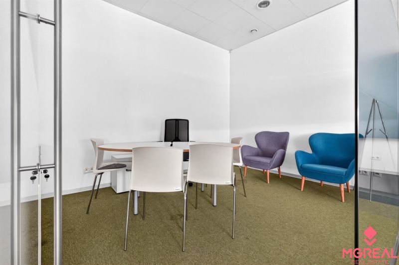 Commercial premises with a conference table, colorful armchairs, and simple chairs.