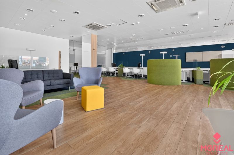 Interior of commercial spaces with wood-patterned flooring, gray furniture, and green elements.