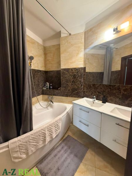 A bathroom with a bathtub, sink, and elegant tiles in a 3-room apartment.