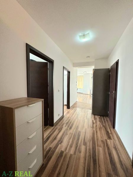 A hallway in a 3-room apartment with a wooden decor floor and white walls.