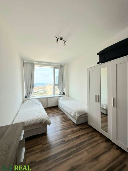 A room with two beds and a wardrobe, a floor with a wooden decor in a 3-room apartment.