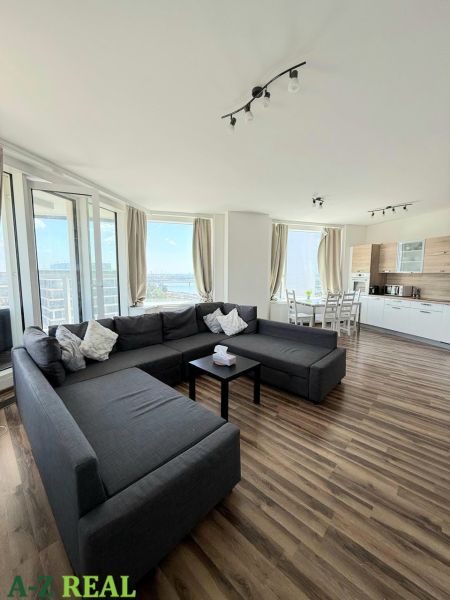 Living room with a large sofa, dining table, and floor with wooden decor.