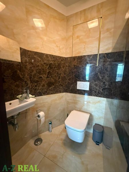 A toilet with a sink in a 3-room apartment, stone cladding and flooring.