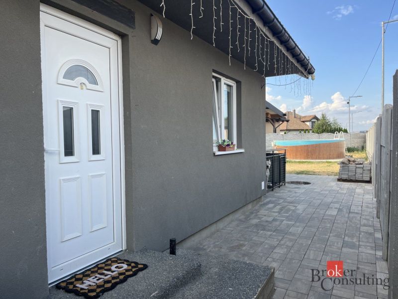 The family house on SNP Street in Čaňa has a gray facade and a landscaped garden with a swimming pool.