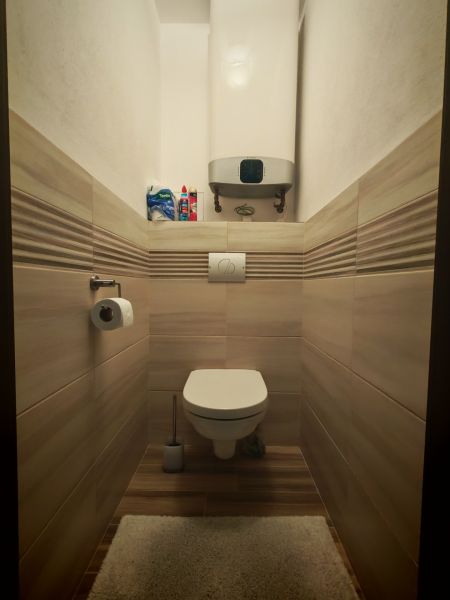 Bathroom in a 2-room apartment with a toilet, tiled walls and floor with a wood decor.
