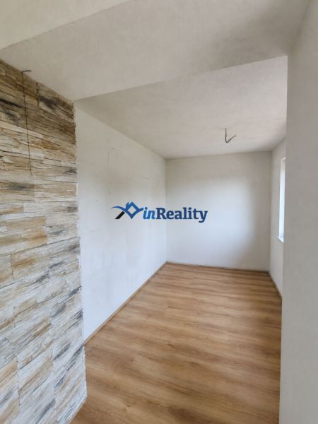 A room in a family house with a wooden decor floor and stone cladding on the wall.
