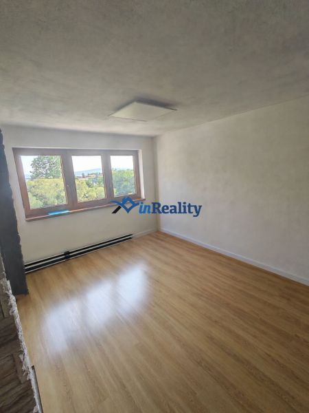 A room with a wooden decor floor in a family house, large window and white walls.