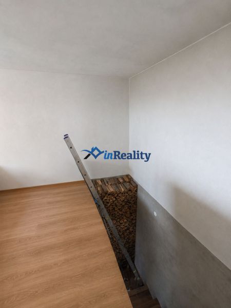 Family house: ladder, wooden decor flooring, stacked wood, white walls.