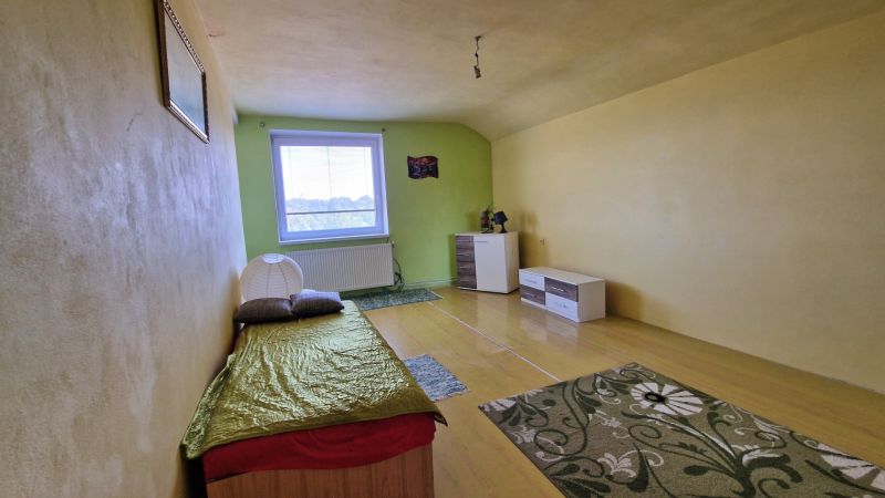 A simple room with a bed, light-colored walls, and a floor with a wooden decor.