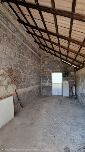A shed with a sloped metal roof and concrete walls, located in a family house.