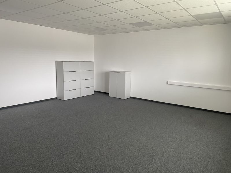 Empty office space with white furniture and gray carpet.