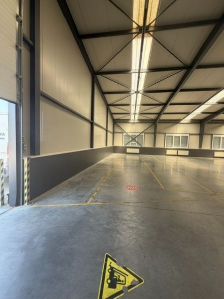 Interior of a warehouse hall with a concrete floor and steel structure.