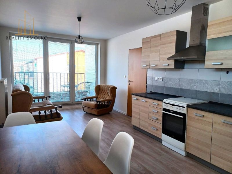 Living room with sofas, kitchen unit, and floor with wood decor in a two-room apartment.