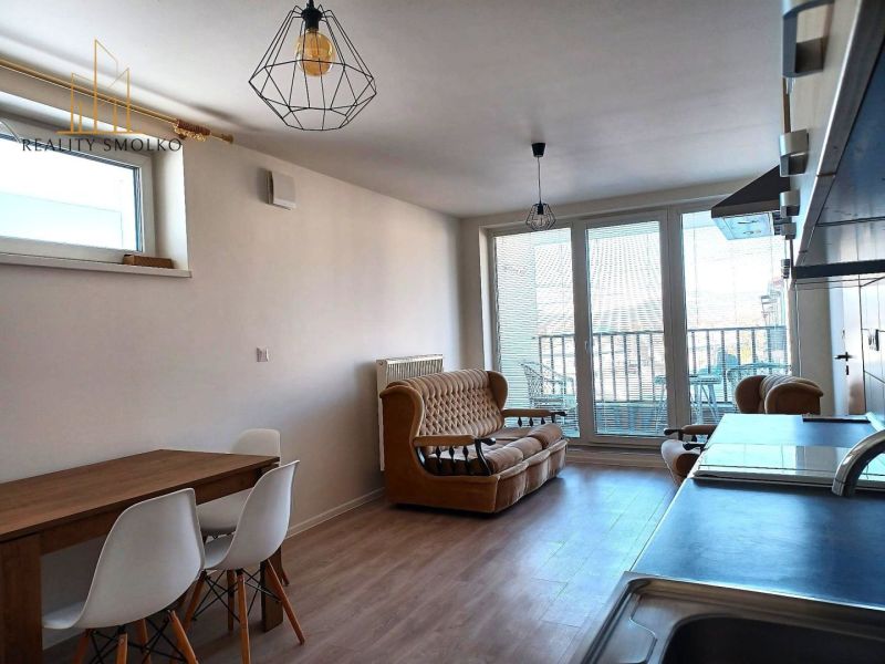 Living room in a two-room apartment with a couch, table, and large windows to the terrace.
