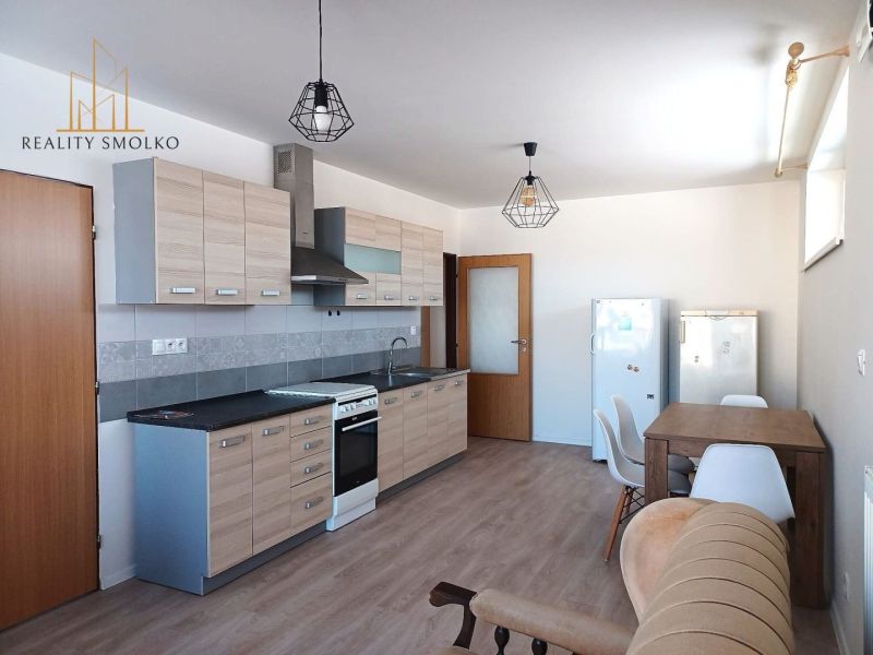 A kitchen in a 2-room apartment with a wooden decor floor and a dining table.