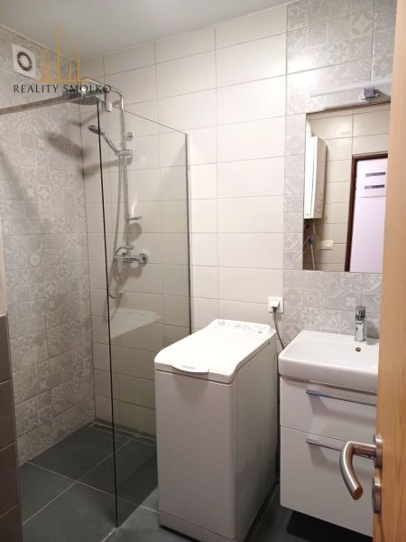 Bathroom in a 2-room apartment with a washing machine, shower, and sink.