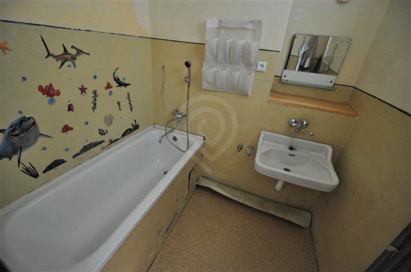 A bathroom in a 2-room apartment with a bathtub and sea wall decoration.