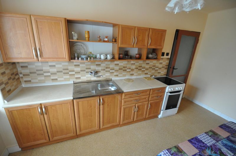 A kitchen with wooden cabinets and mosaic tiles in a 2-room apartment.