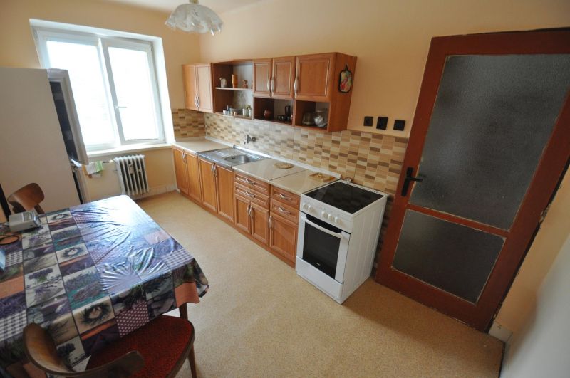 The kitchen of a 2-room apartment with a dining table, kitchen unit, and electric stove.