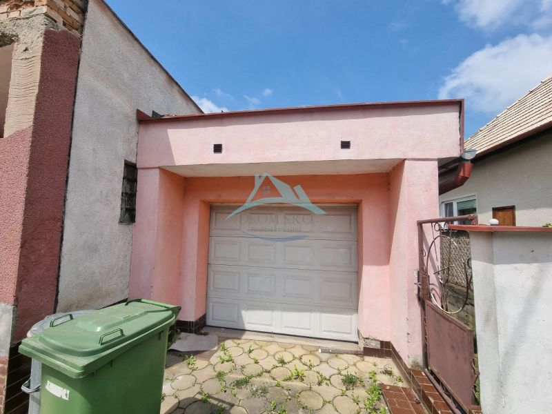 A family house on Šípošová Street in Šahy with a garage and waste bins.