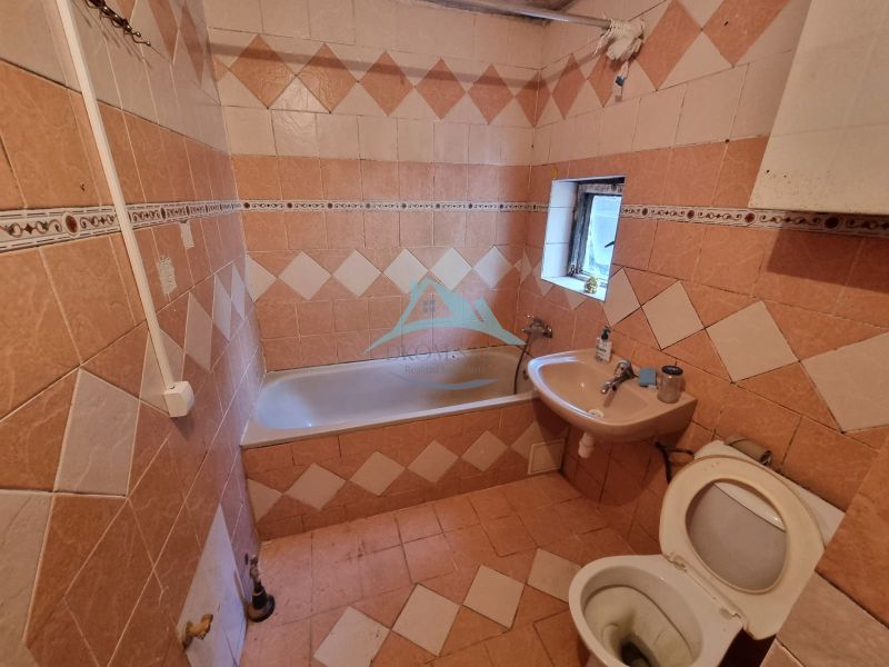 A bathroom with tiles and cladding, a bathtub, a sink, and a toilet in a family house.
