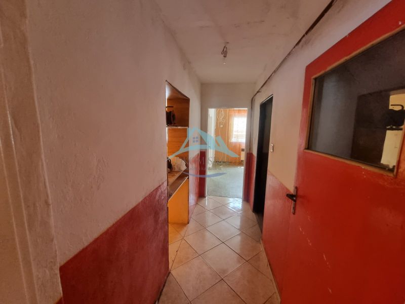 A hallway in a family house with a tiled floor and red doors.
