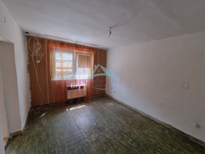 A room in a family house with a floor and windows with curtains.