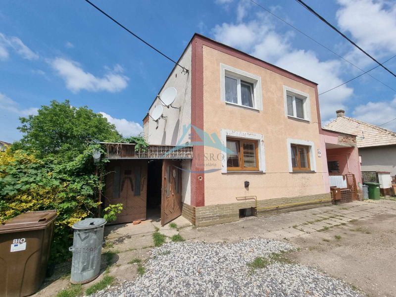 A family house on Šípošova Street in Šahy surrounded by greenery and containers.