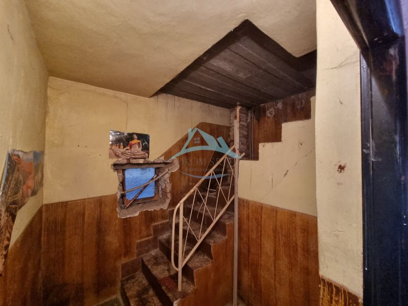 Interior of a family house with a metal staircase, worn-out walls, and a window with wallpaper.