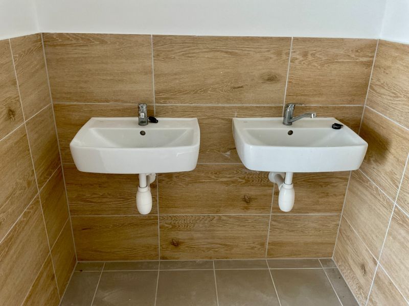 Two sinks on a wall with wood decor tiles in warehouses and halls.