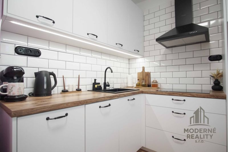 White kitchen unit with wood-patterned floor in a 2-room apartment.