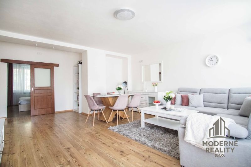 Living room in a two-room apartment with a wooden decor floor and a comfortable sofa.