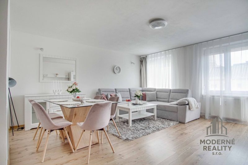 Bright living room with a sofa, dining table, and wood-patterned floor.