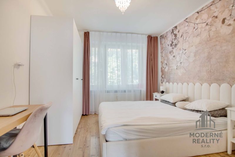 A bright bedroom with a bed and a subtle floral wallpaper decor in a two-room apartment.
