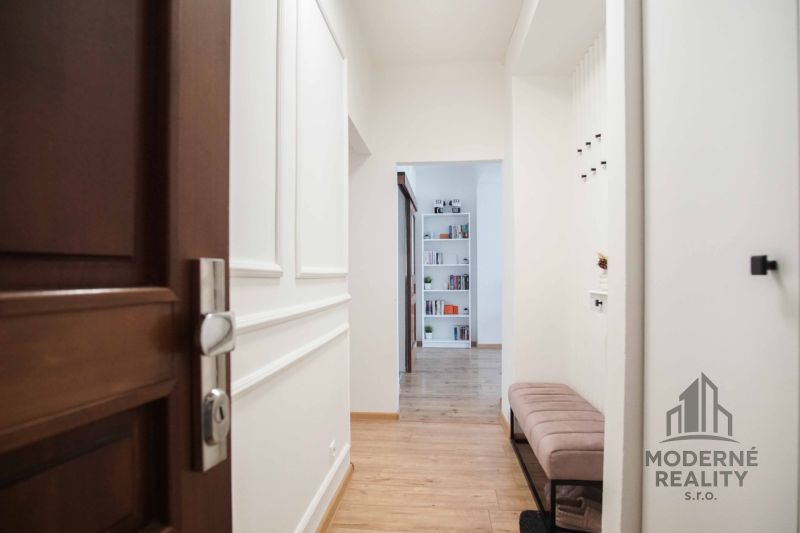 Hallway with wood-patterned flooring, open door, bookshelf, bench.