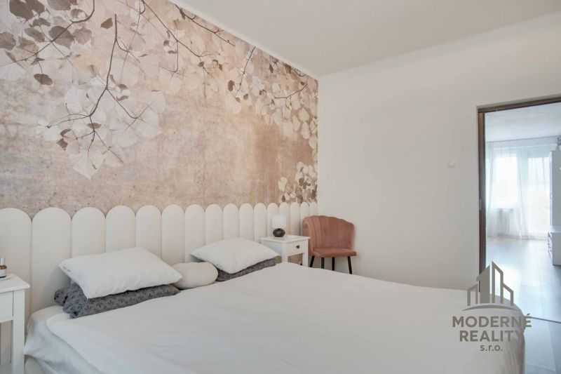 A bedroom in a two-room apartment with wall decorations of flowers and light furniture.