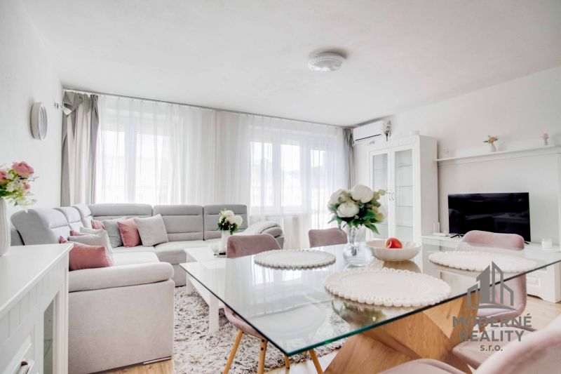 Living room in a two-room apartment with a white sofa and a glass table.