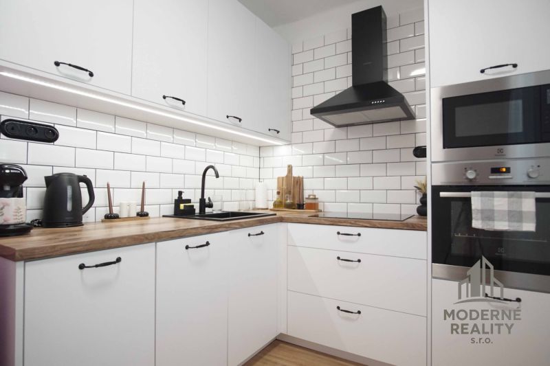 A kitchen in a 2-room apartment with white cabinets and a wood-patterned floor.
