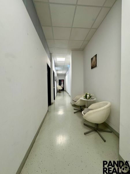 A corridor in commercial premises with white walls and white chairs.