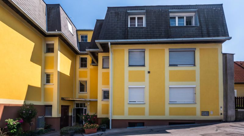 Yellow apartment building with a dark roof on Babenbergerstraße in Hainburg an der Donau.