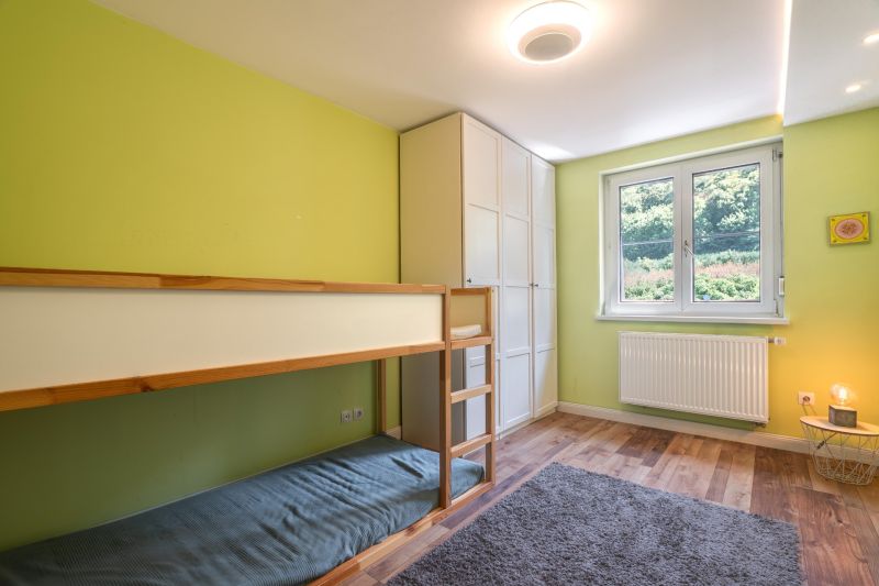 Green wall in a 4-room apartment with a bunk bed and wooden decor flooring.