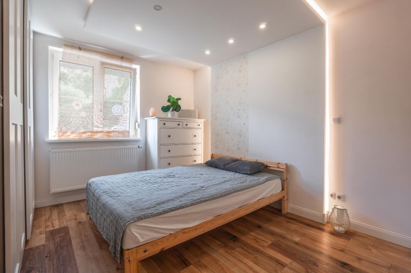 A bedroom with a gray curtain, a dresser, and a bed in a 4-room apartment with wood-patterned flooring.