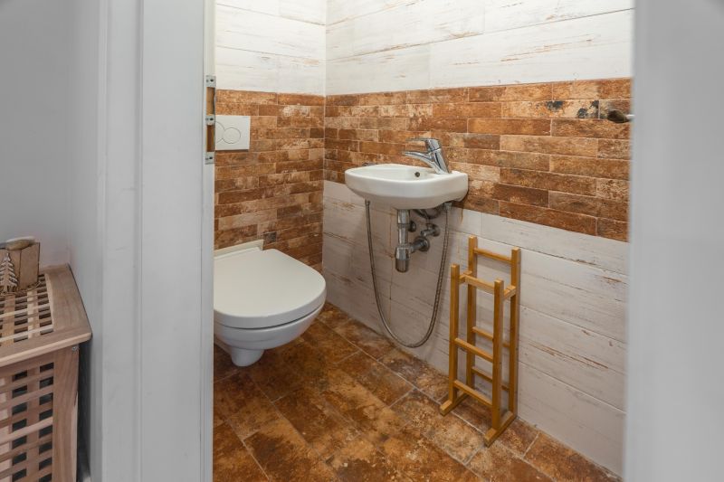Bathroom in a 4-room apartment with a toilet, sink, and decorative wall tiles.