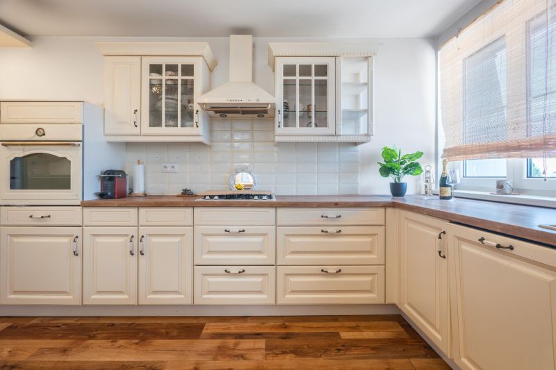 A kitchen with beige cabinets, wood-patterned flooring, a plant, and appliances in a 4-room apartment.