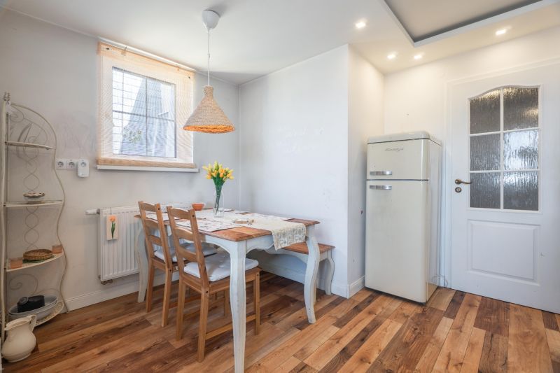 A bright kitchen with a table, chairs, flowers, and a wooden decor floor in a 4-room apartment.