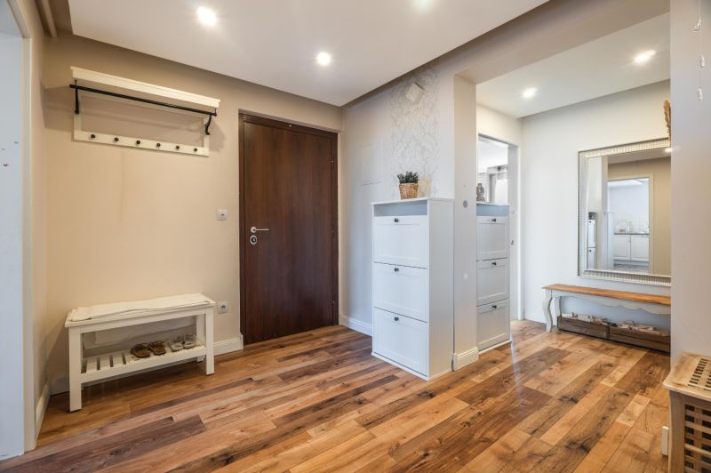 Entrance to a 4-room apartment with a wooden decor floor, cabinets, and a mirror.