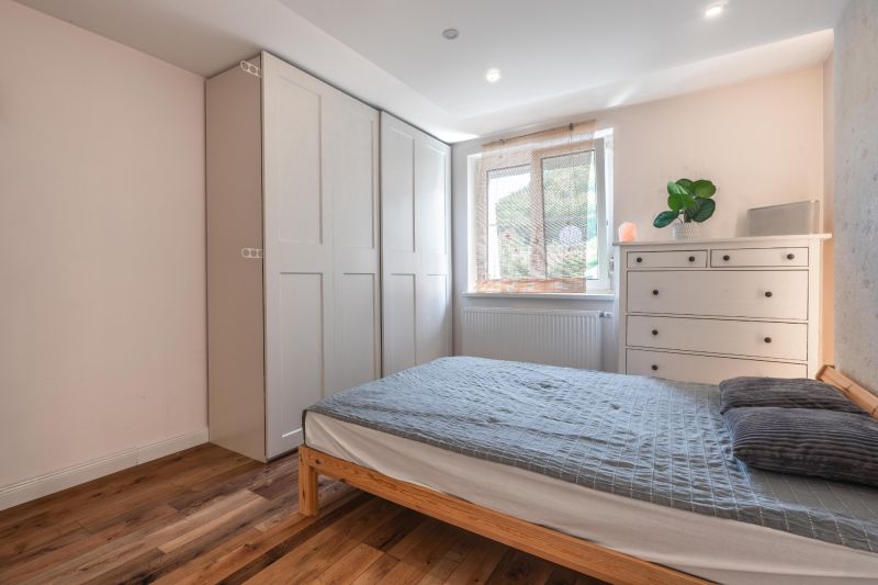A bedroom in a 4-room apartment with a wooden decor floor, a bed, and a wardrobe.